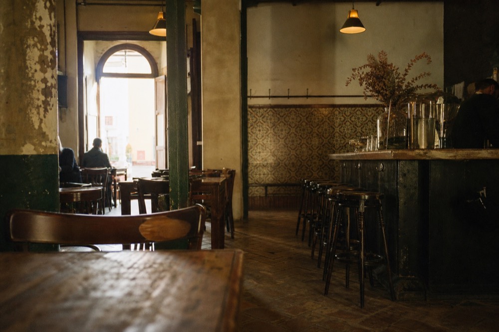 Rustic bar interior in Seville with worn wooden tables and a clear floor at one end, warm light, no performers yet